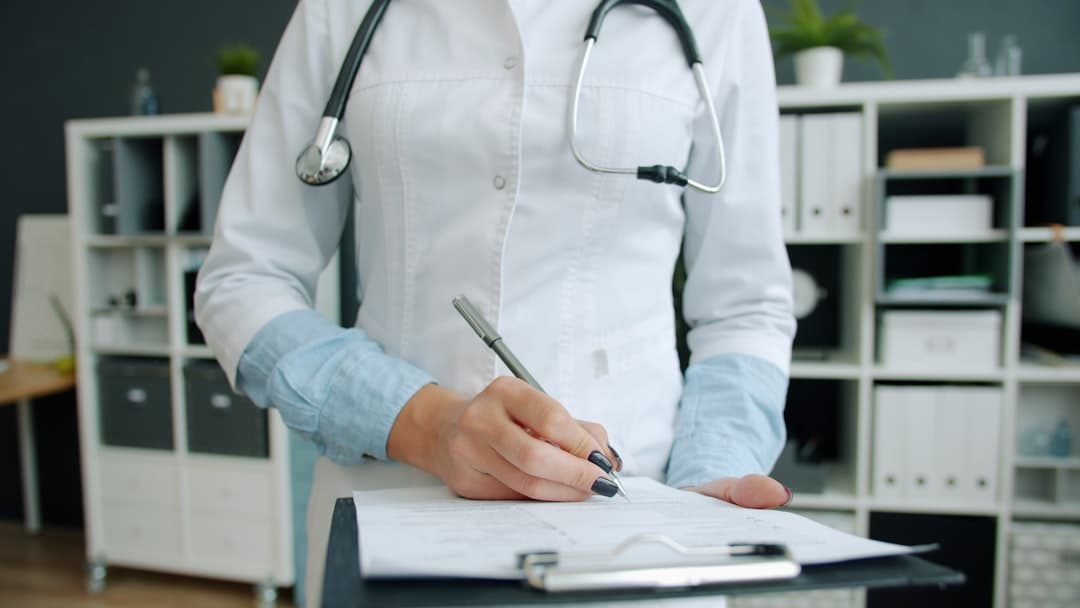 Doctor writing on clipboard in office