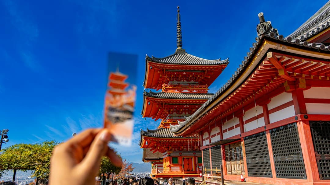 Hand holding a postcard with a temple