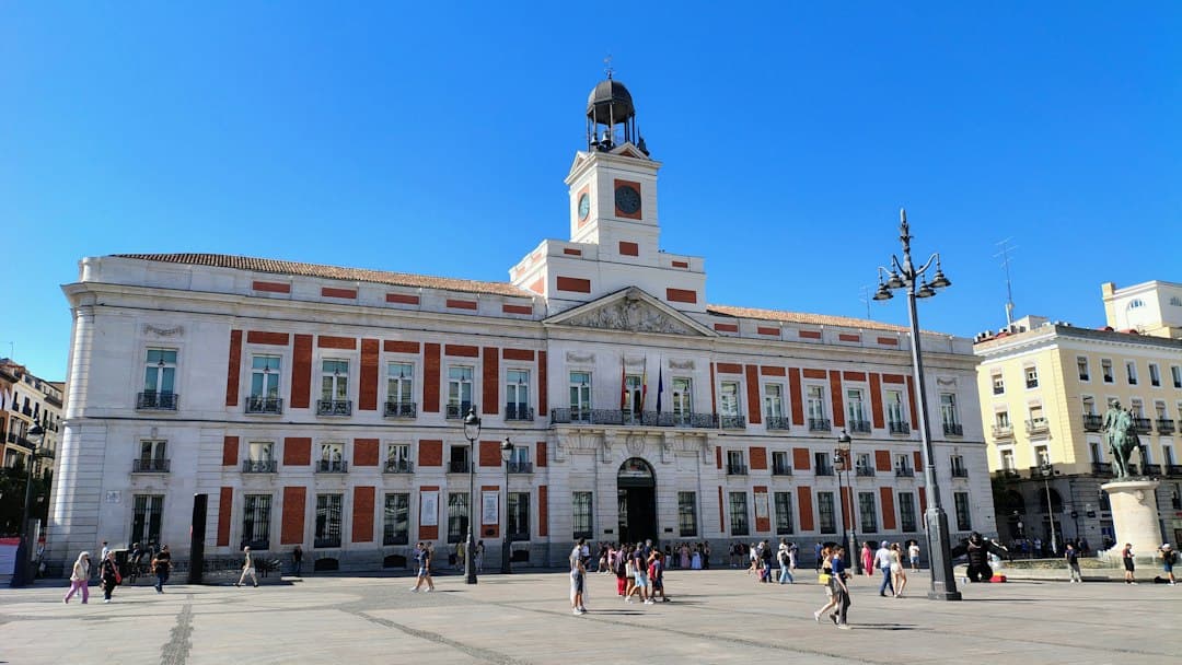 People walking across the plaza outside the Real Casa de Correos in Madrid