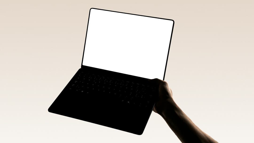 A hand is holding a laptop