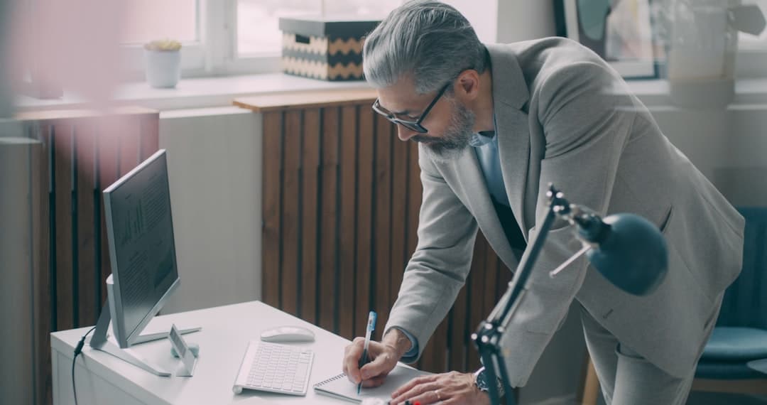 A man in a suit writing on a piece of paper