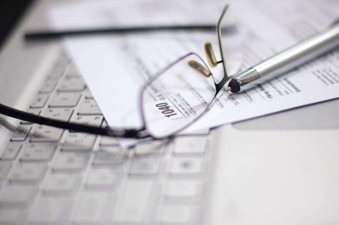 Glasses and pen on tax form and laptop.
