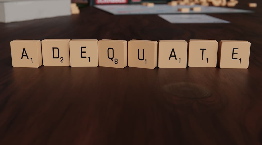 Scrabble tiles spell out the word adequate.