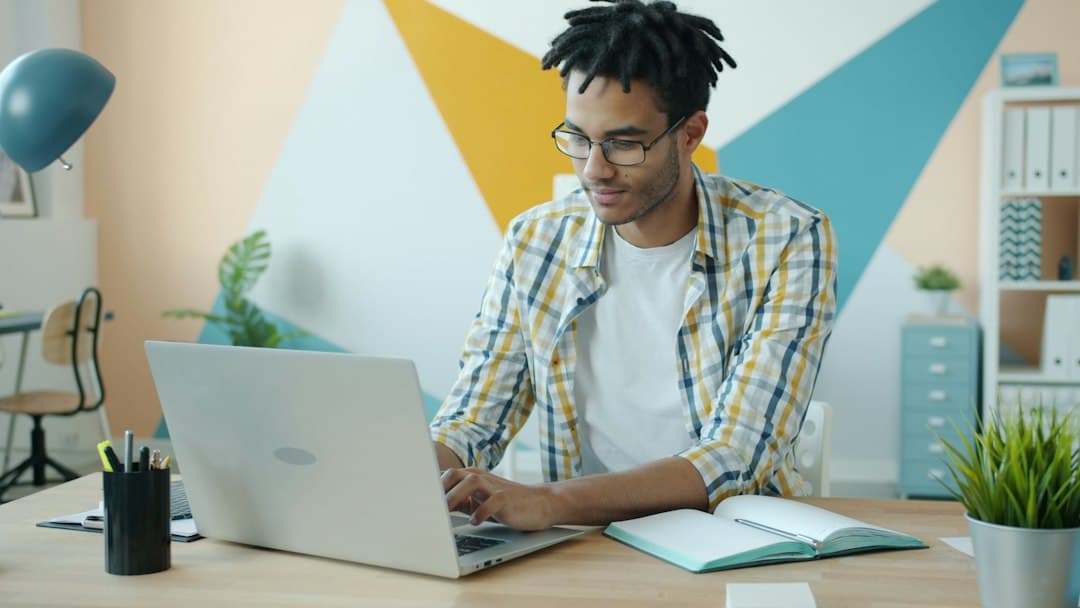 Man working on laptop at desk with colorful wall background