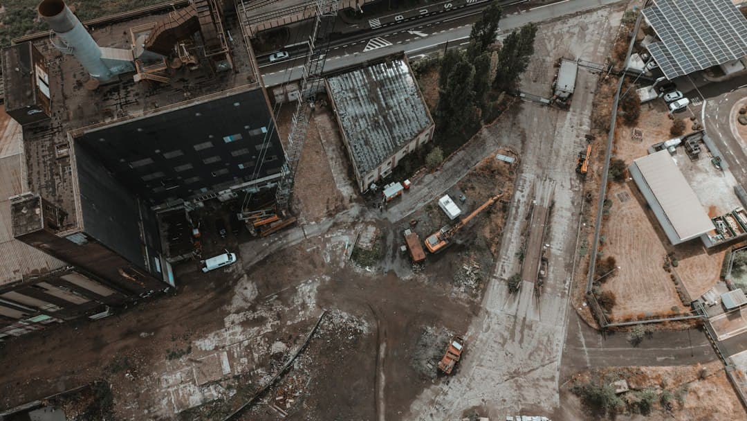 An aerial view of an industrial site with a large building and construction machinery