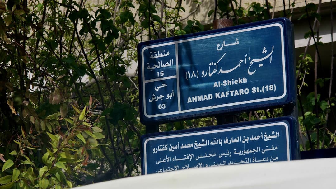 Street signs in arabic and english with building names.